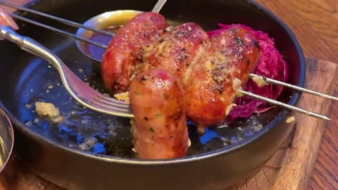 Serving of the baked thick short sausages with leaf vegetables and side dish of Stock Footage 323924034