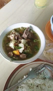 A serving of beef soup with vegetables served on a white bowl with a plate Stock Photos