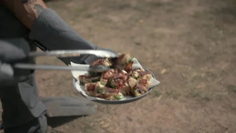 Serving up camp fire cooked Jalapeño Poppers onto a plate Stock Footage 240058008