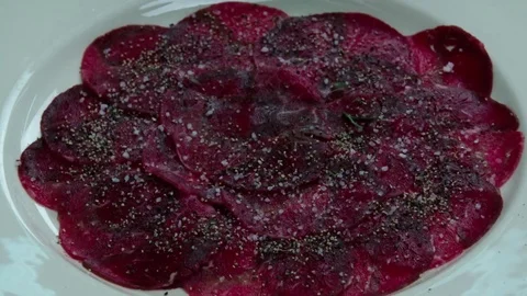 Serving carpaccio meat dish green herbs HD slow motion сlose up video top view Stock Footage 70007055