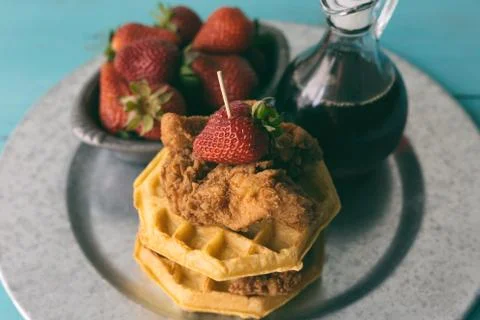 Serving of chicken and waffles with strawberries. Stock Photos