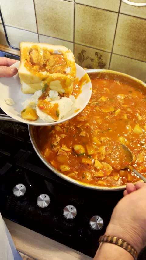 Serving chicken curry into hollowed out white bread to make bunny chow Vidéo 341547324