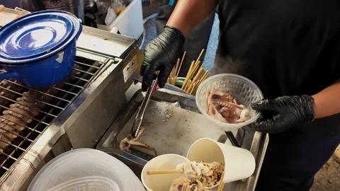 Serving cooked squid skewers into plastic container Stock-Footage 347585569