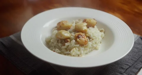 Serving creamy seafood risotto with seared scallops onto white plate. Close up Vídeos de archivo 330136614