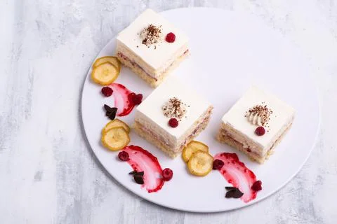 Serving of delicious fruit vanilla cake pieces on a white plate Stock Photos