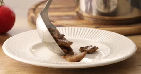 Serving the dish. Cooked meat from the pan is placed on a plate. Stock Footage 250020414