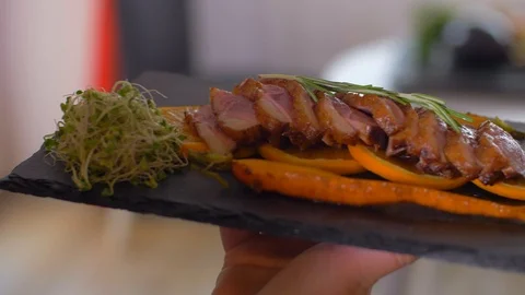 Serving a dish of duck breasts on an orange sofa Stock Footage 110041526