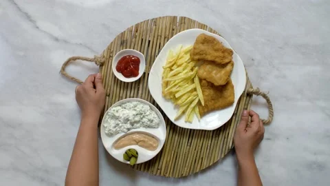 Serving a dish of fried fish fillet, French fries, salad, and sauce, top view Stock Footage 135181800