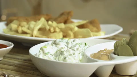 Serving a dish of fried fish fillet, French fries, salad, and sauce Stock Footage 135185867