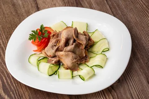 Serving a dish from the restaurant menu. Sliced beef tongue with cucumber on  Stock Photos