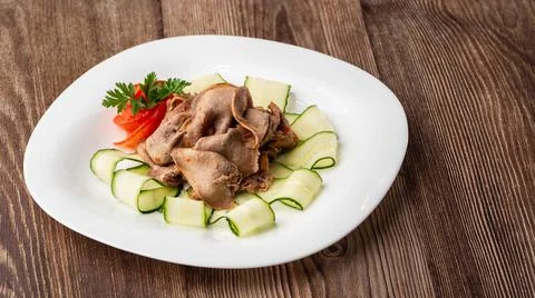 Serving a dish from the restaurant menu. Sliced beef tongue with cucumber on  Stock Photos