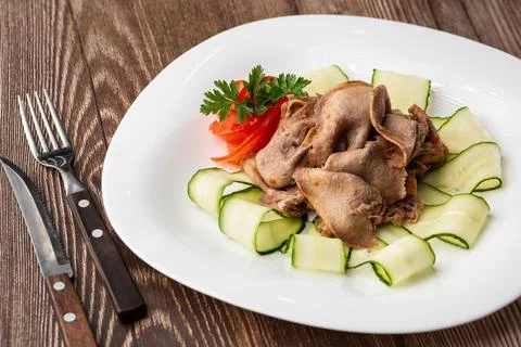 Serving a dish from the restaurant menu. Sliced beef tongue with cucumber on  Stock Photos