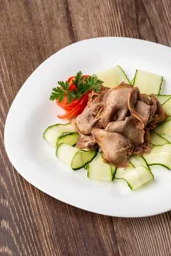 Serving a dish from the restaurant menu. Sliced beef tongue with cucumber on  Stock Photos