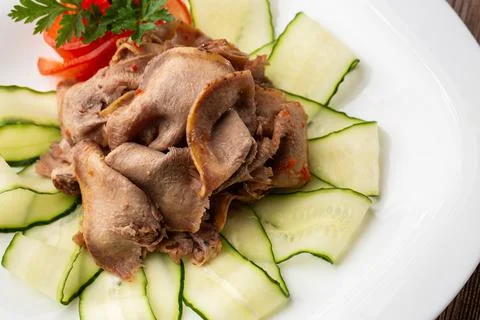Serving a dish from the restaurant menu. Sliced beef tongue with cucumber on  Stock Photos