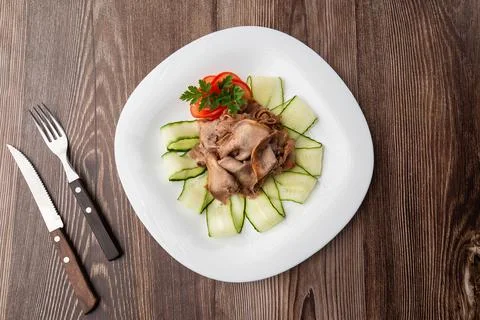 Serving a dish from the restaurant menu. Sliced beef tongue with cucumber on  Stock Photos