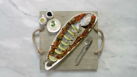 Serving a dish of roasted fish with vegetables and sauce. Top view Stock Footage 135287699
