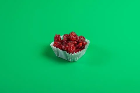 A serving of dried cherries in a paper muffin cup on a green background. Foto stock