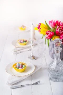 Serving Easter table with colorful sweet eggs in cases on the plates, crystal Stock Photos