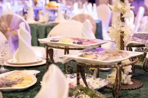 Serving a festive table on a green tablecloth before the arrival of guests in Stock Photos