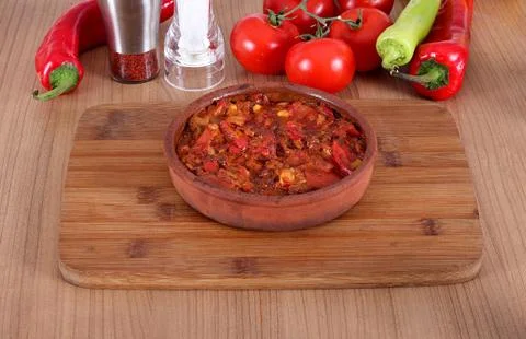 Serving fresh meat in earthenware dish with red and green pepper Stock Photos