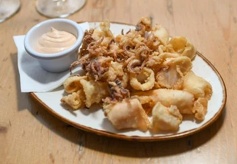 A serving of fried squid with garlic sauce in a European restaurant Stock Photos