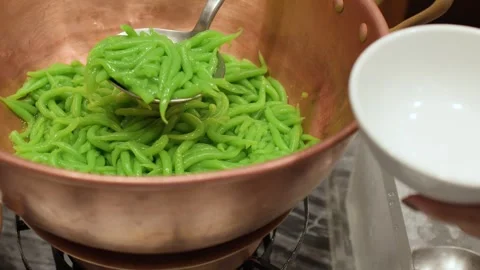 Serving Green Pandan Noodles from a Copper Pot at a Buffet Stock Footage 334829063