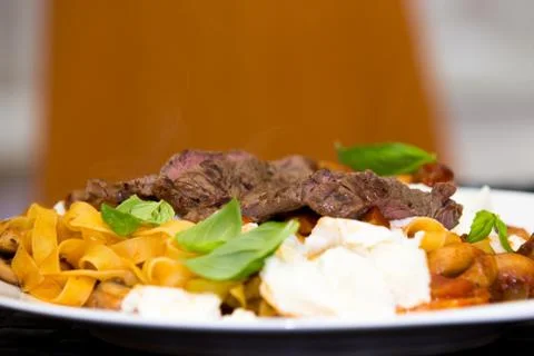 Serving of grilled beef steak and pasta Stock Photos