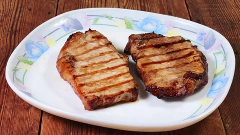 Serving of grilled pork steaks on plate on rustic table Stock Footage 345670169