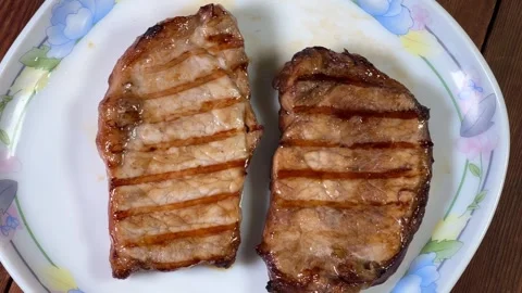 Serving of grilled pork steaks on plate on rustic table Stock Footage 345670184