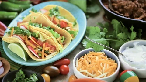Serving ground beef tacos with romaine lettuce, diced tomatoes, radishes, and sh Stock Footage