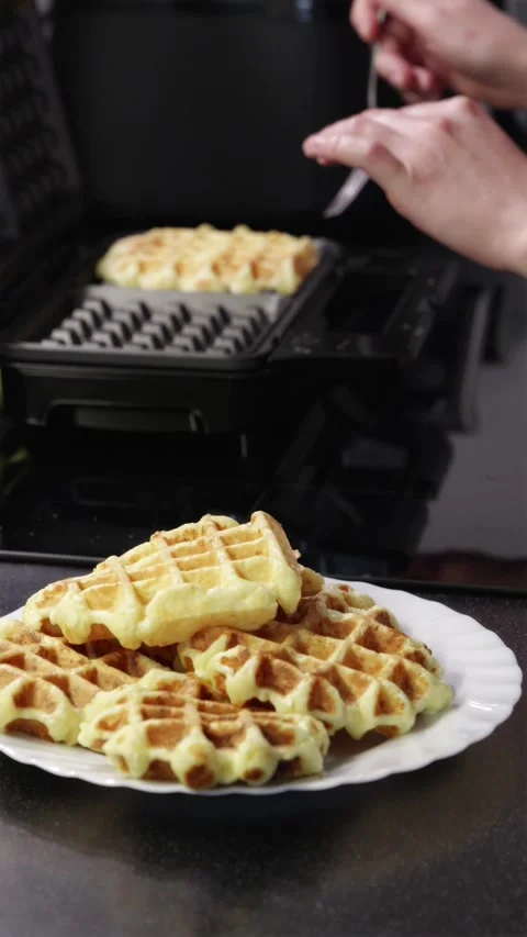 Serving hot steaming waffles from electric iron onto ceramic plate Stock Footage 336902541