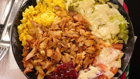 A serving of kebab on a plate the chicken, rice, sauce, and salad Stock Footage 345572670