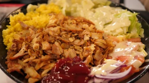 A serving of kebab on a plate the chicken, rice, sauce, and salad Stock Footage 345572679