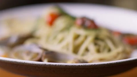 A serving of long spaghetti pasta in a large light plate, sprinkled with herbs Stockbeeldmateriaal 256156752