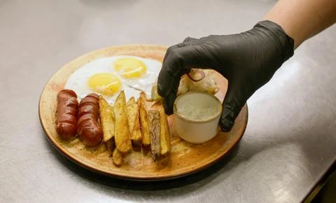 Serving lunch meal plate fried egg sausages chef Stock Photos