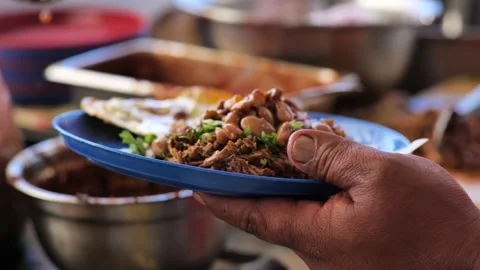 A serving of Mexican birria (stewed beef) receives a spoonful of meat Stock Footage 147406674