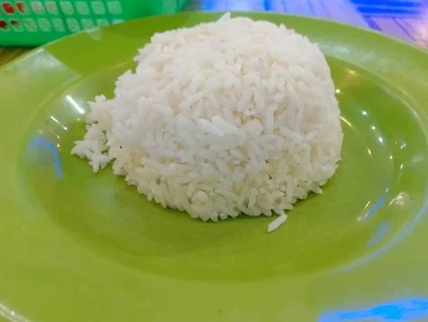 A serving of plain white rice is on a bright green plate, ready to eat Stock Photos
