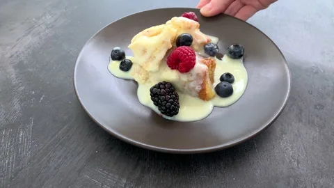 Serving a Plate of Bread Pudding with Custard and Berries Video stock 218312122