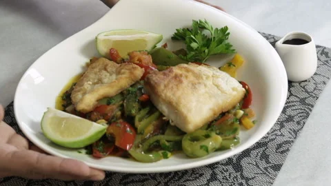 Serving a plate of roasted fish slices with boiled vegetables and sauce Stock Footage 135290254