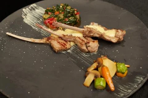Serving rack of lamb on a plate. vegetable stew. White sauce Stock Photos