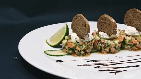 Serving a salad with lime and bread in a white plate on a black background in 4k Stock Footage 99223413