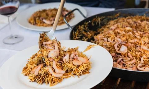 Serving seafood noodles onto a plate at the dining table Stock Photos