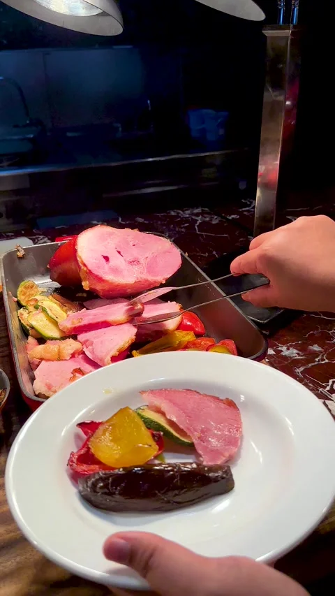 Serving Sliced Roasted Ham and Grilled Vegetables at a Buffet Stock Footage 335620779
