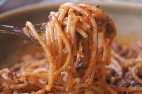 Serving spaghetti with sauce on a fork at a table Stock Photos