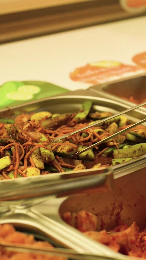 Serving Spicy Cucumber Kimchi and Korean Side Dishes at a Buffet Stock-Footage 340381048