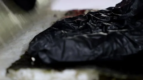 Before serving, the sushi chef sprinkles sesame seeds on the sushi with gloves. Stock Footage 323362963