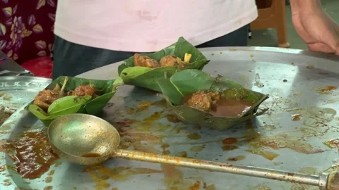 Serving of tasty mutton curry pieces on natural leaf plates at a roadside stall Stock Footage 294768758