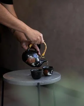 Serving tea with a special ceramic teapot over two small tea cups Stock Photos