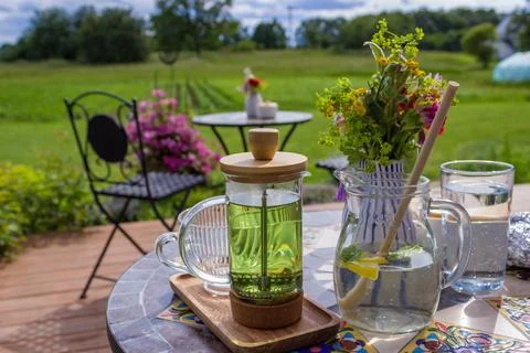 Serving tea with a teapot in a rustic bistro with a vium in flover's garden Stock-Fotos
