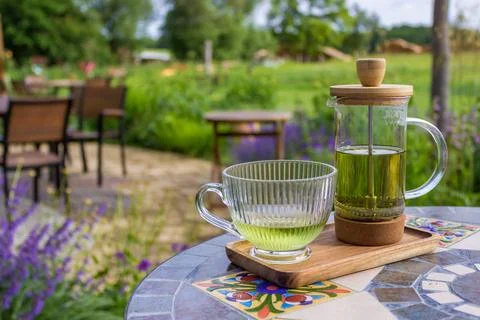 Serving tea with a teapot in a rustic bistro with a vium in flover's garden Stock Photos